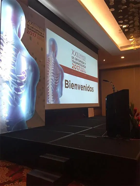 Escenario de un congreso de ortopedia y traumatología 2017, con pantalla de bienvenida y panel lateral con imagen de columna vertebral