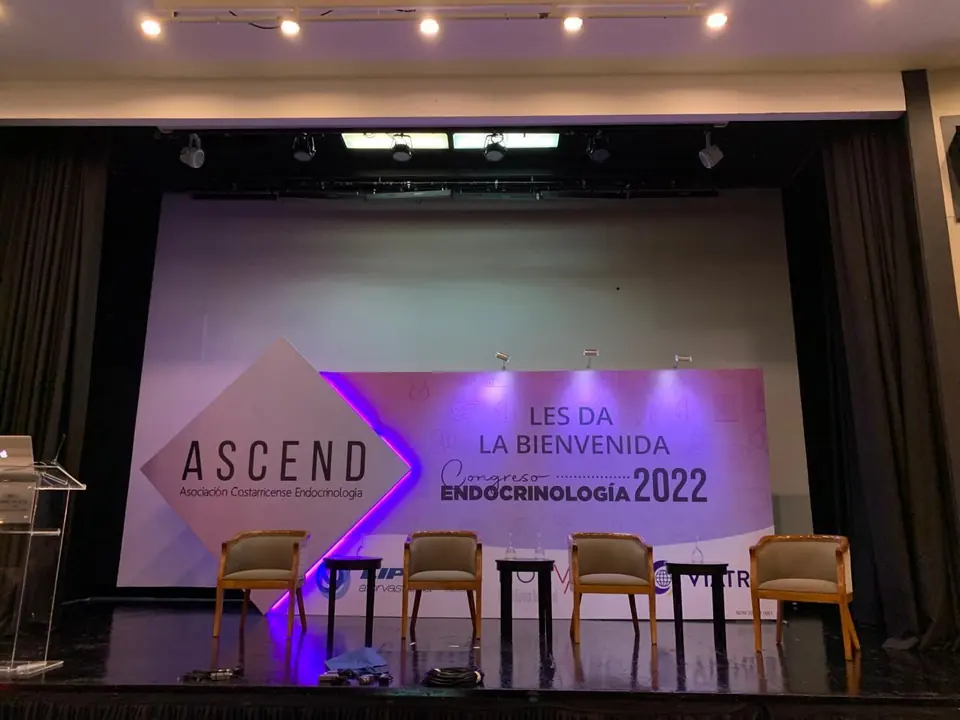 Escenario del Congreso Endocrinología 2022 de ASCEND, con backdrop de bienvenida y rombo retroiluminado en violeta