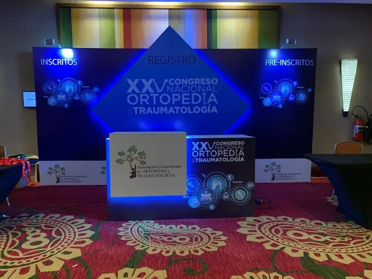 Área de registro del XXV Congreso Nacional de Ortopedia y Traumatología, con backdrop retroiluminado y mostrador a medida