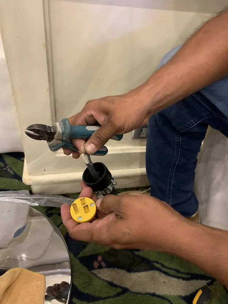 Manos de un técnico conectando con pinzas el cableado de la iluminación de una pieza en sitio