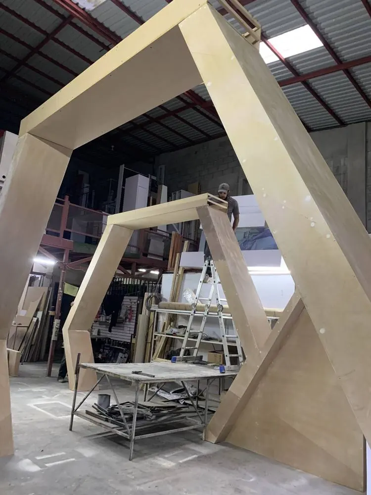 Dos operarios armando en el taller un pórtico de gran formato antes de trasladarlo al montaje